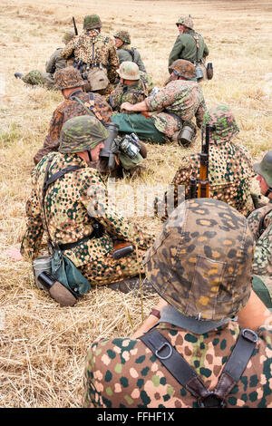 la-segunda-guerra-mundial-re-promulgacion-grupo-de-aleman-waffen-ss-patron-de-puntos-soldados-en-uniformes-de-camuflaje-sentada-y-esperando-en-la-hierba-amarilla-ffhf1x.jpg